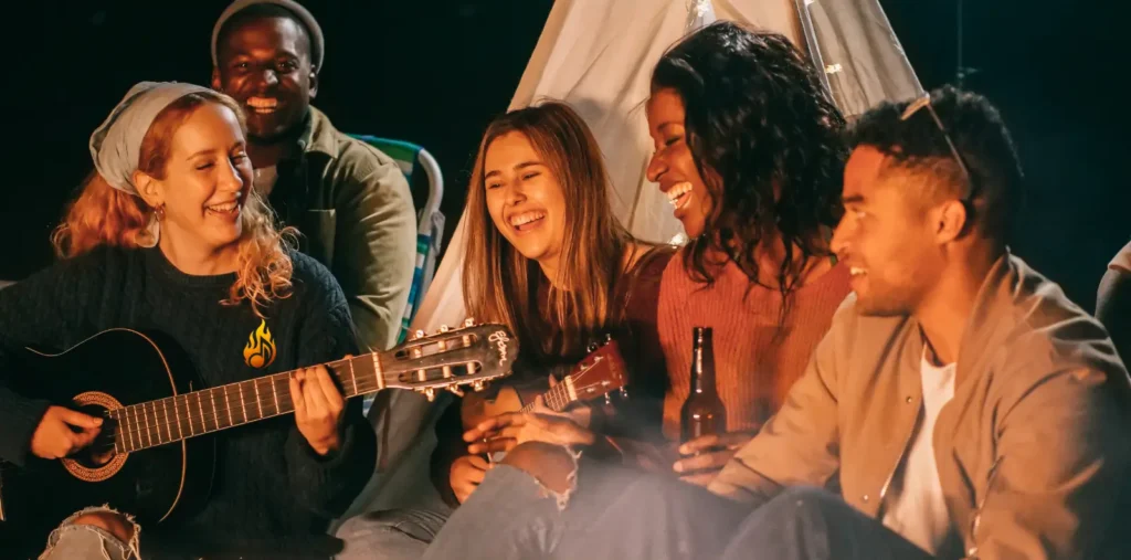 Blue Chords: The Emotional Backbone of Blues Music Group of friends enjoying a campfire with Blue Chords music on guitar and ukulele, cozy tent setting.